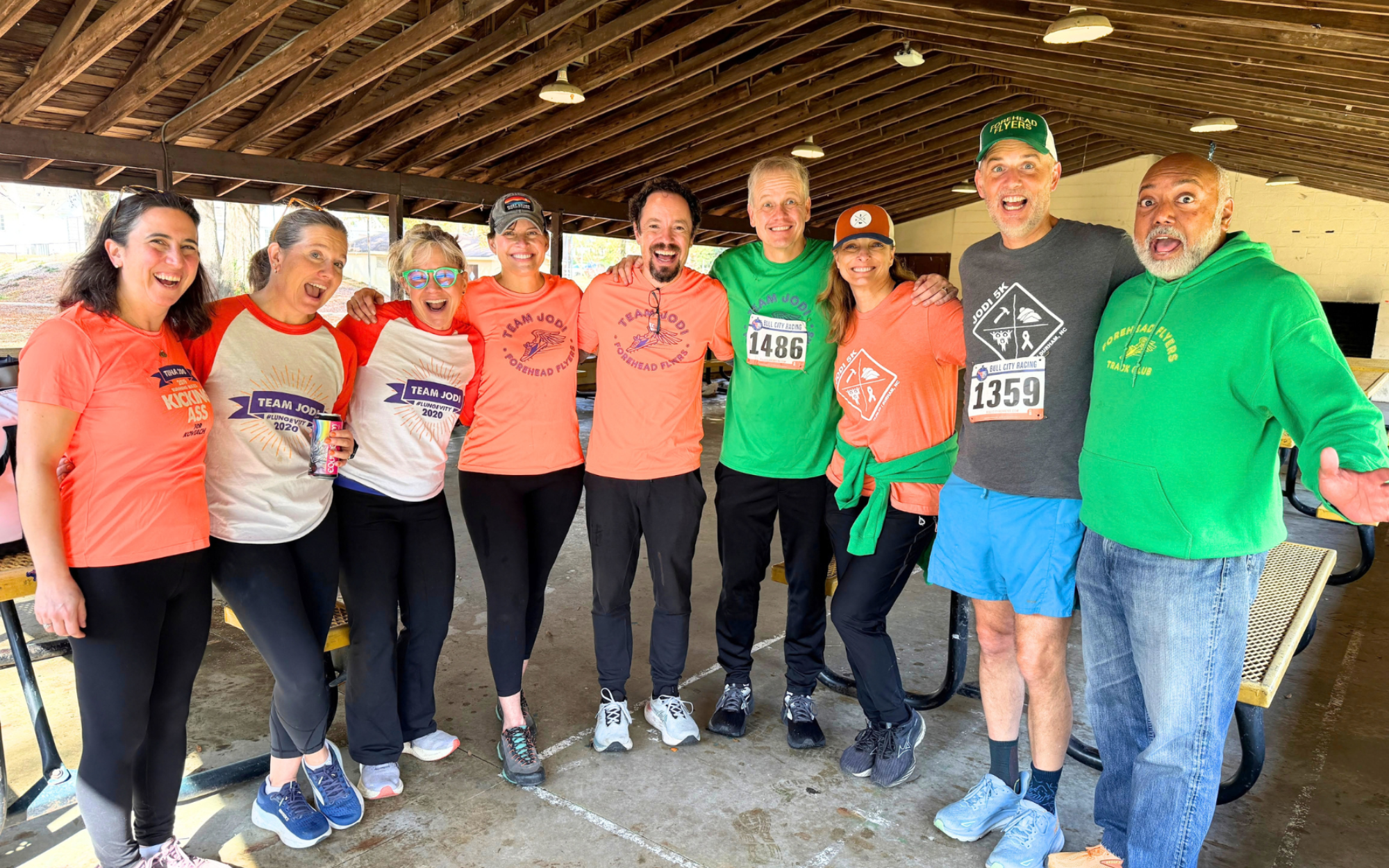 Members of the Jodi 5K Committee and the Forehead Flyers in Team Jodi shirts, laughing together under a park shelter